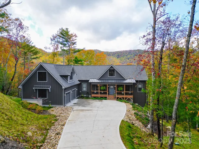a view of a house with a big yard plants and large tree