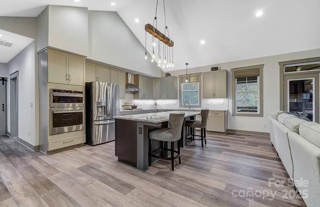 a kitchen with stainless steel appliances a dining table chairs stove refrigerator and cabinets