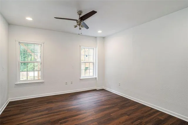 a view of an empty room with wooden floor and a window