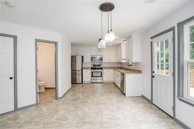 a kitchen with white cabinets stainless steel appliances and a window