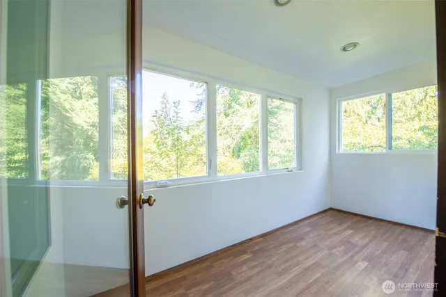 a view of an empty room with wooden floor and a window
