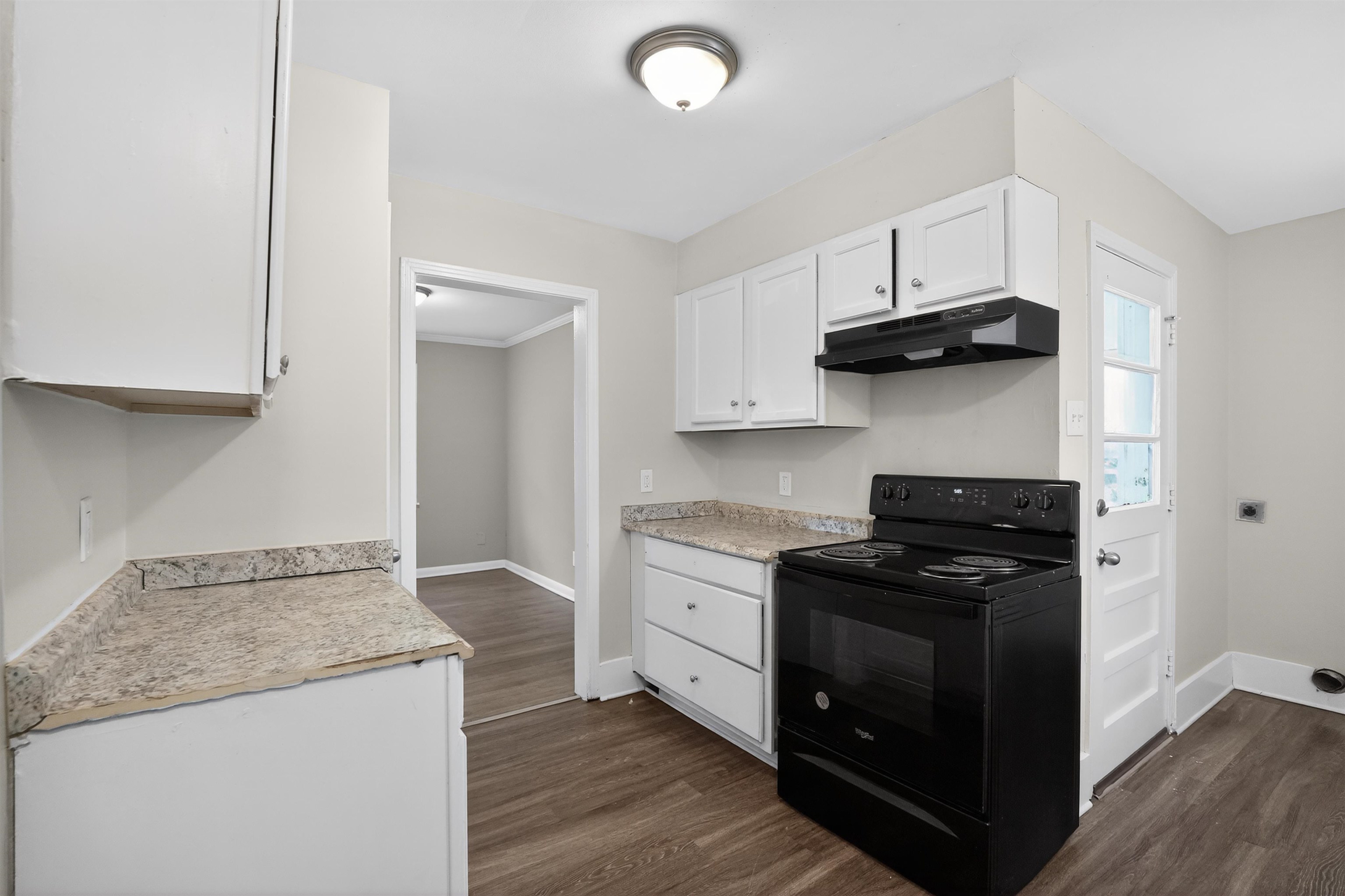 1514 Mt Moriah Road Memphis, TN 38117 - Photo 22 of 34 Kitchen featuring wood-finish flooring, white cabinetry, granite-style countertops, a black electric range, and a black range hood