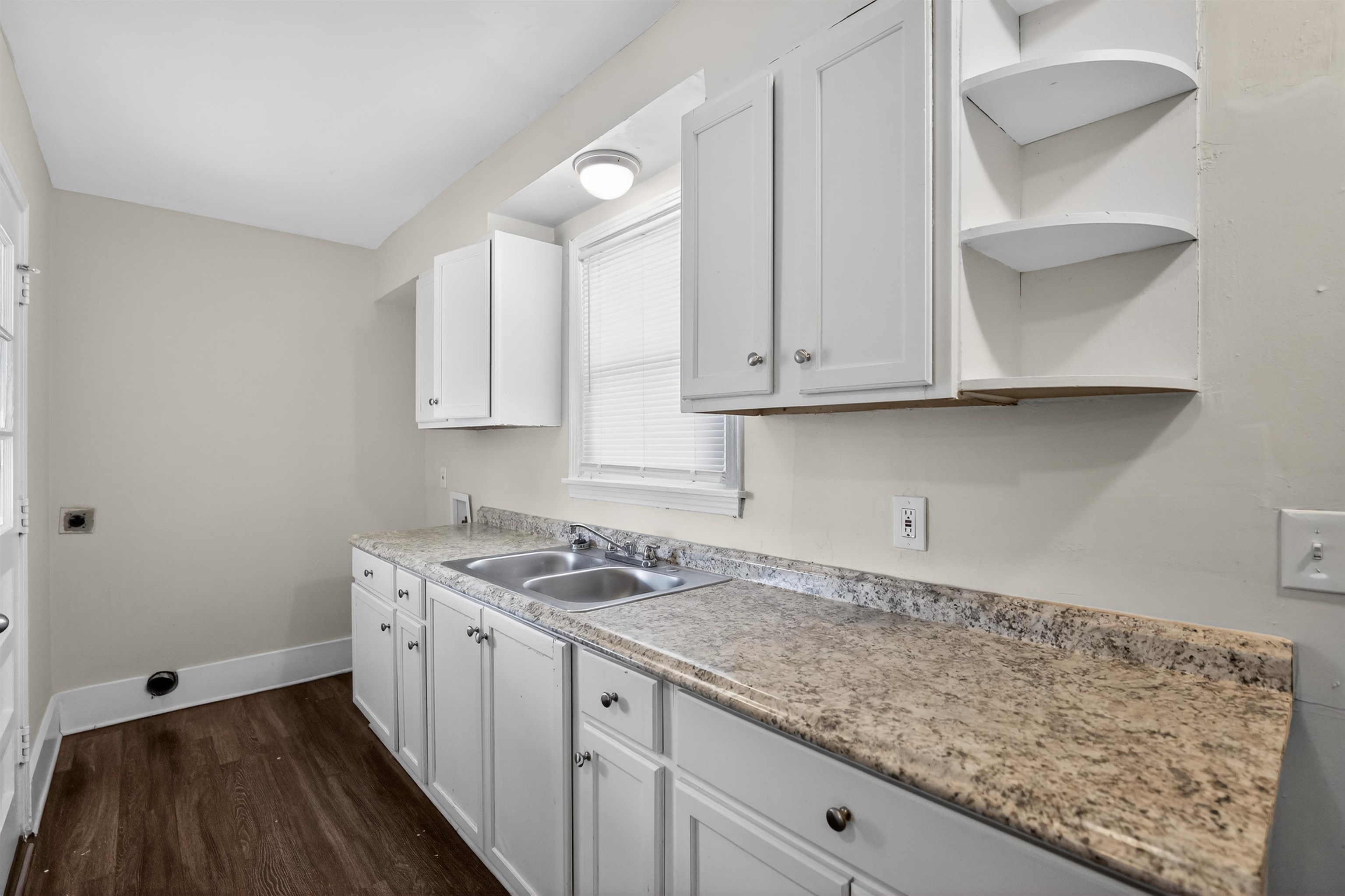 1514 Mt Moriah Road Memphis, TN 38117 - Photo 25 of 34 Kitchen area featuring white cabinetry, a double basin stainless steel sink, granite-look countertops, and wood-finish flooring