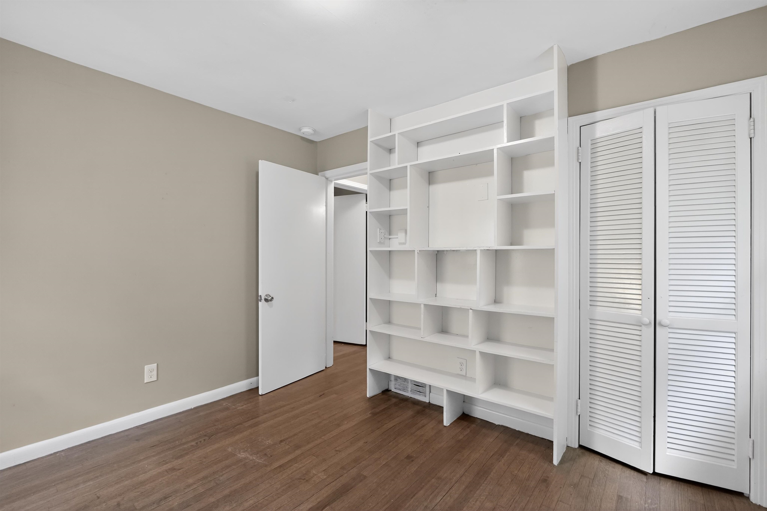 1514 Mt Moriah Road Memphis, TN 38117 - Photo 27 of 34 Room featuring extensive built-in shelving, wood-finish flooring, and neutral wall tones