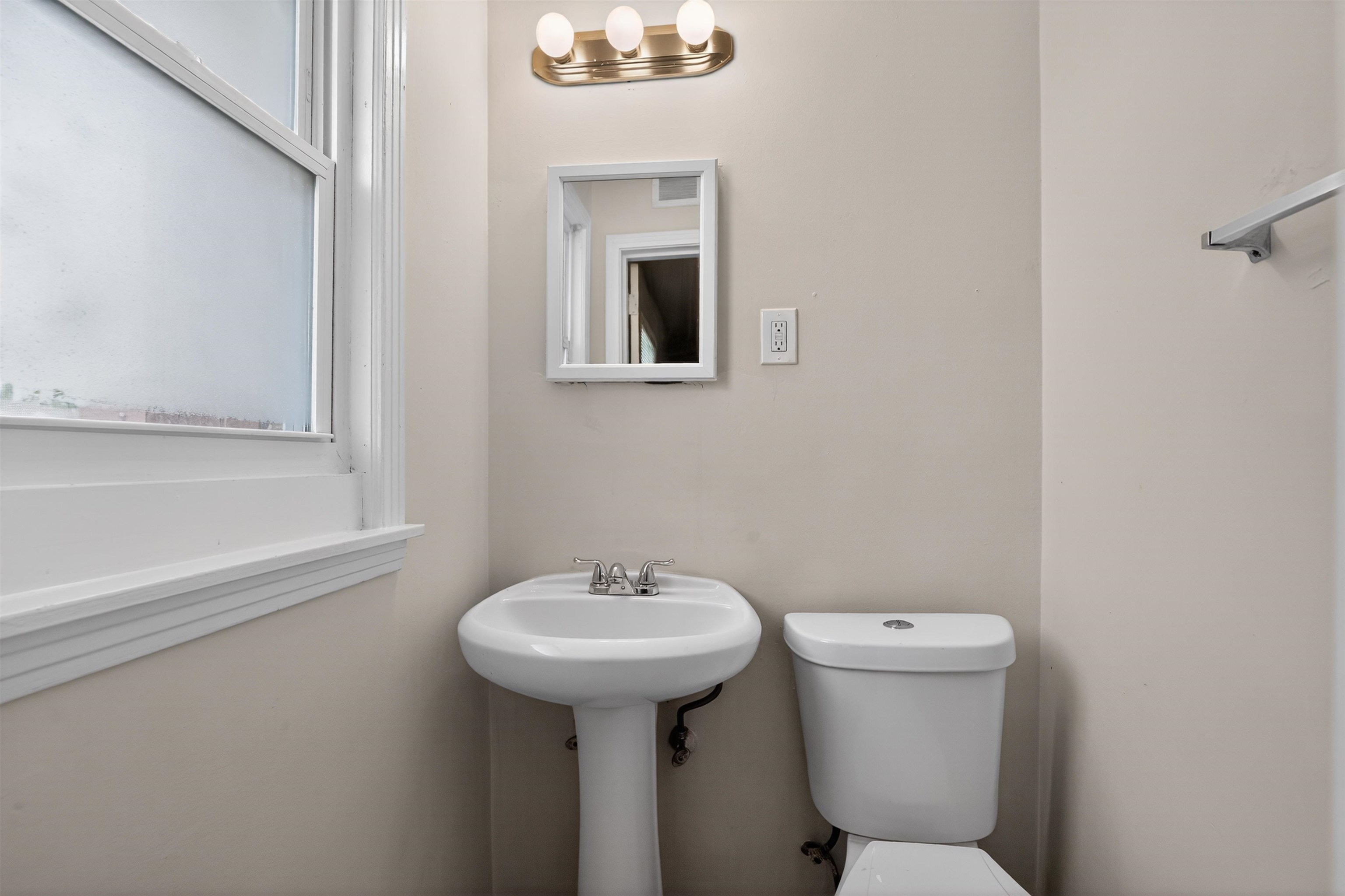 1514 Mt Moriah Road Memphis, TN 38117 - Photo 29 of 34 Pedestal sink with chrome faucet, toilet, wall-mounted mirror, and frosted window