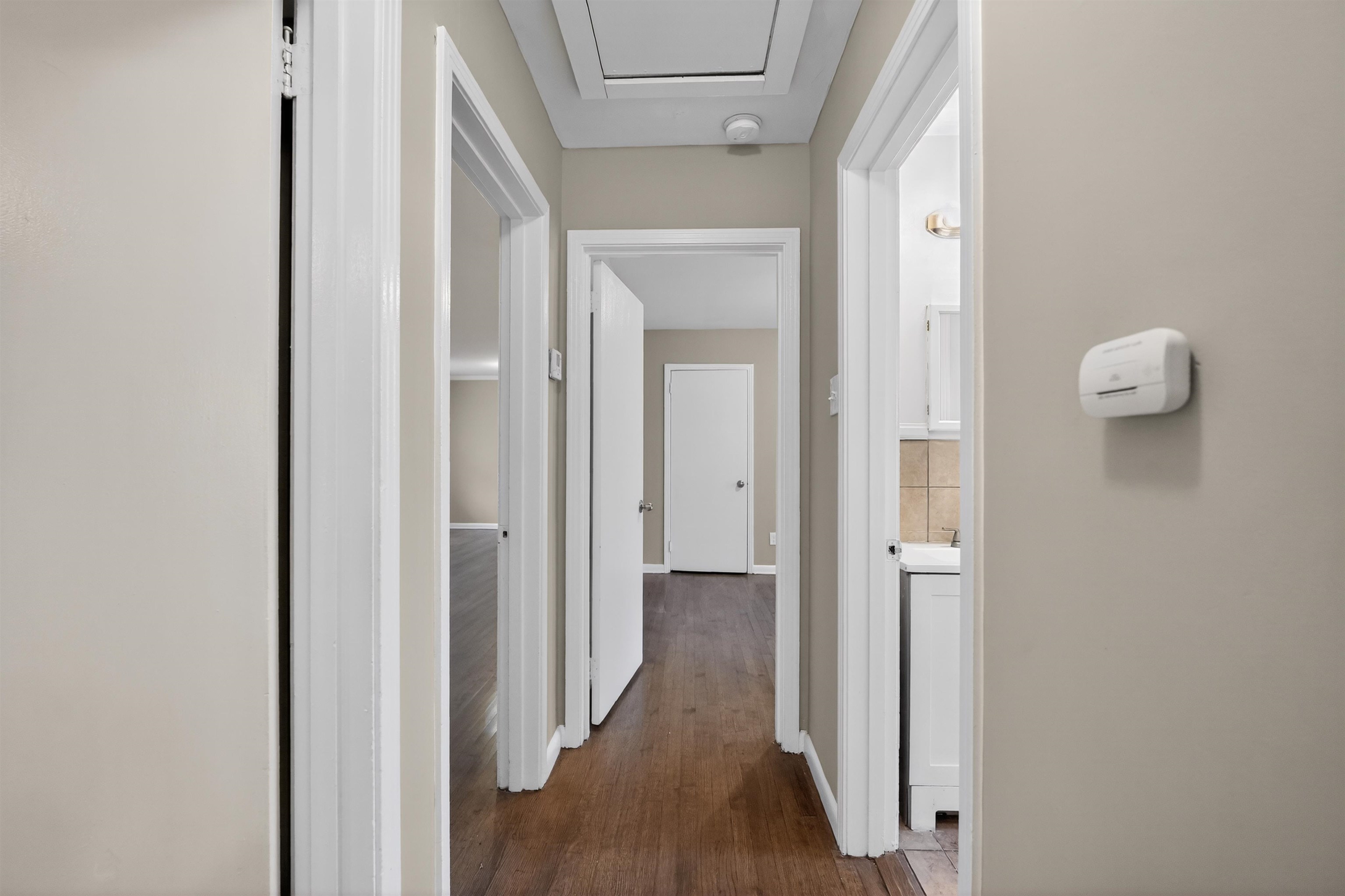 1514 Mt Moriah Road Memphis, TN 38117 - Photo 33 of 34 Hallway with wood-finish flooring, light neutral wall paint, white trim, and multiple doorways