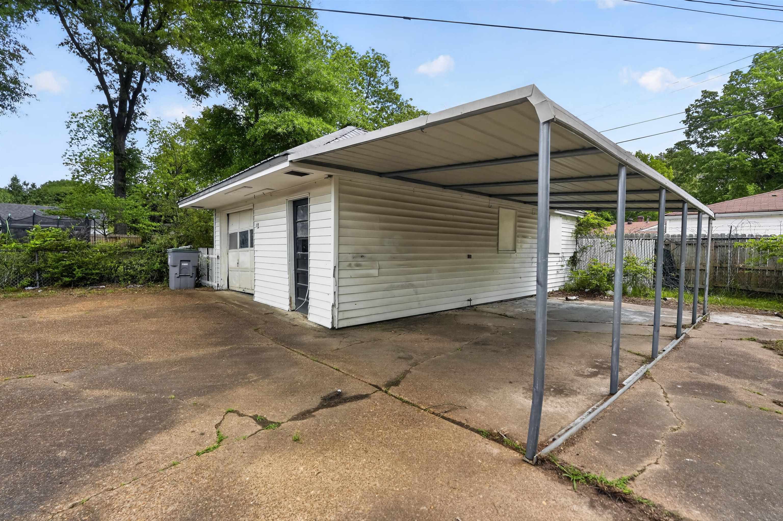 1514 Mt Moriah Road Memphis, TN 38117 - Photo 4 of 34 Detached garage featuring white horizontal siding, a roll-up garage door, and an attached metal carport