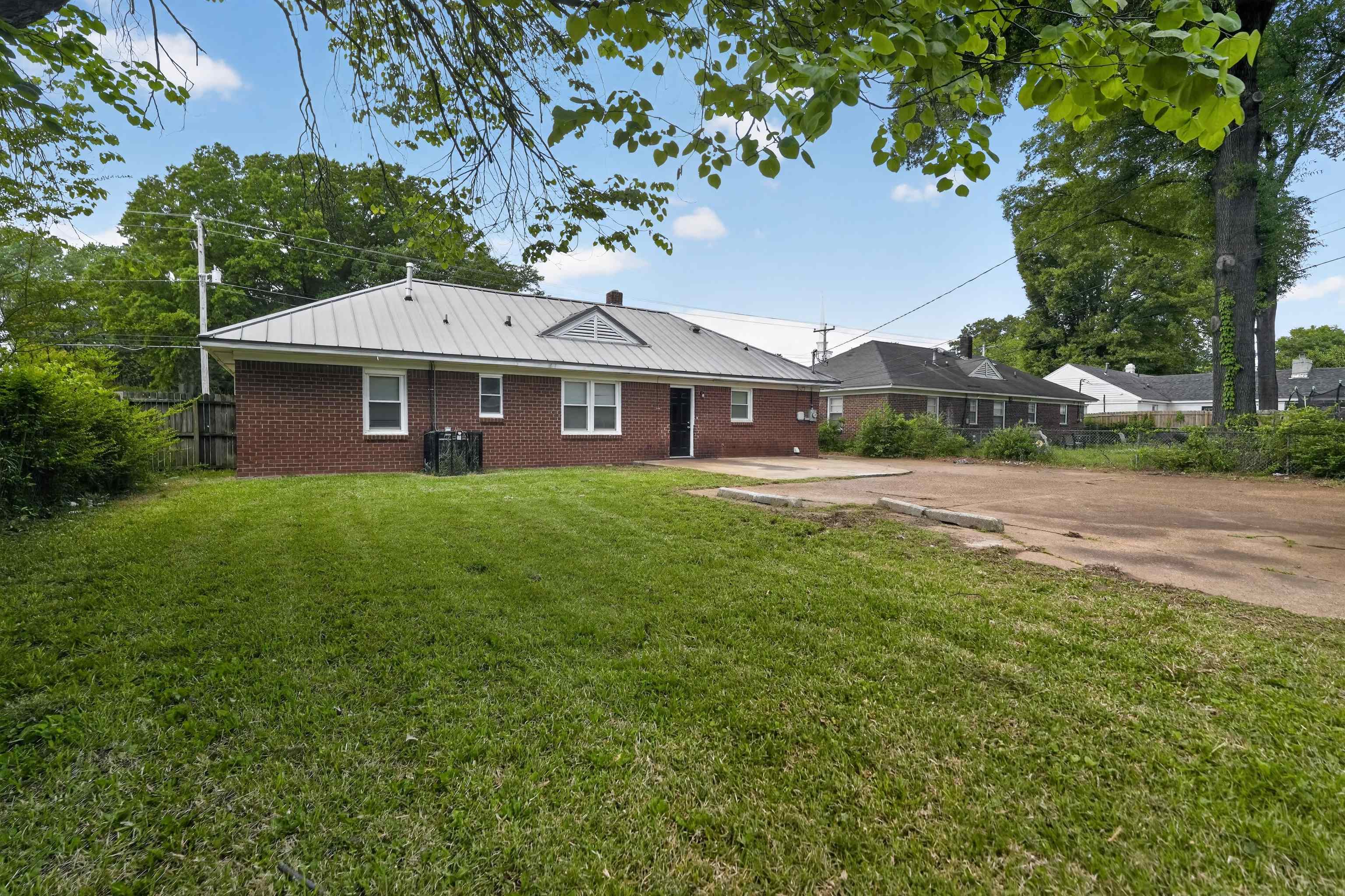 1514 Mt Moriah Road Memphis, TN 38117 - Photo 7 of 34 Expansive green space featuring a brick exterior, metal roof, privacy fencing, and a concrete patio