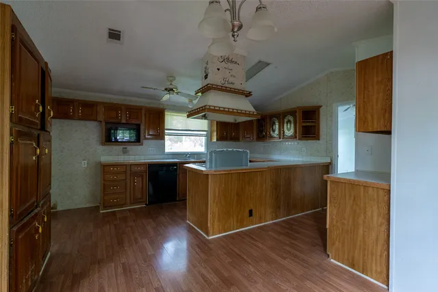 a kitchen with stainless steel appliances granite countertop a refrigerator a stove top oven a sink and dishwasher with wooden floor