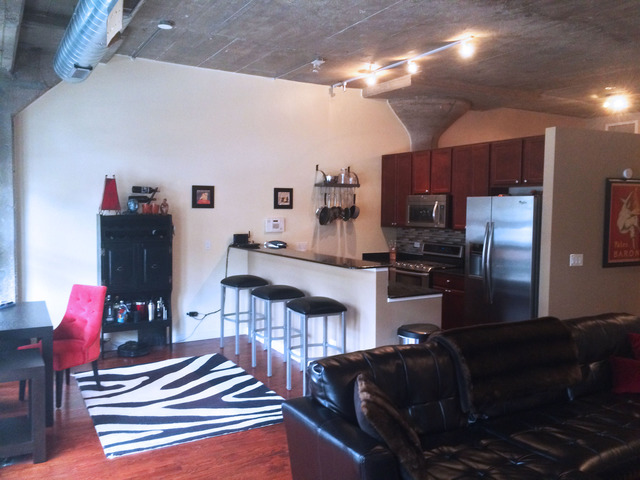 1111 West 15th Street, Unit 126 Chicago, IL 60608 - Photo 5 of 24 a kitchen with stainless steel appliances kitchen island granite countertop a refrigerator and a stove top oven