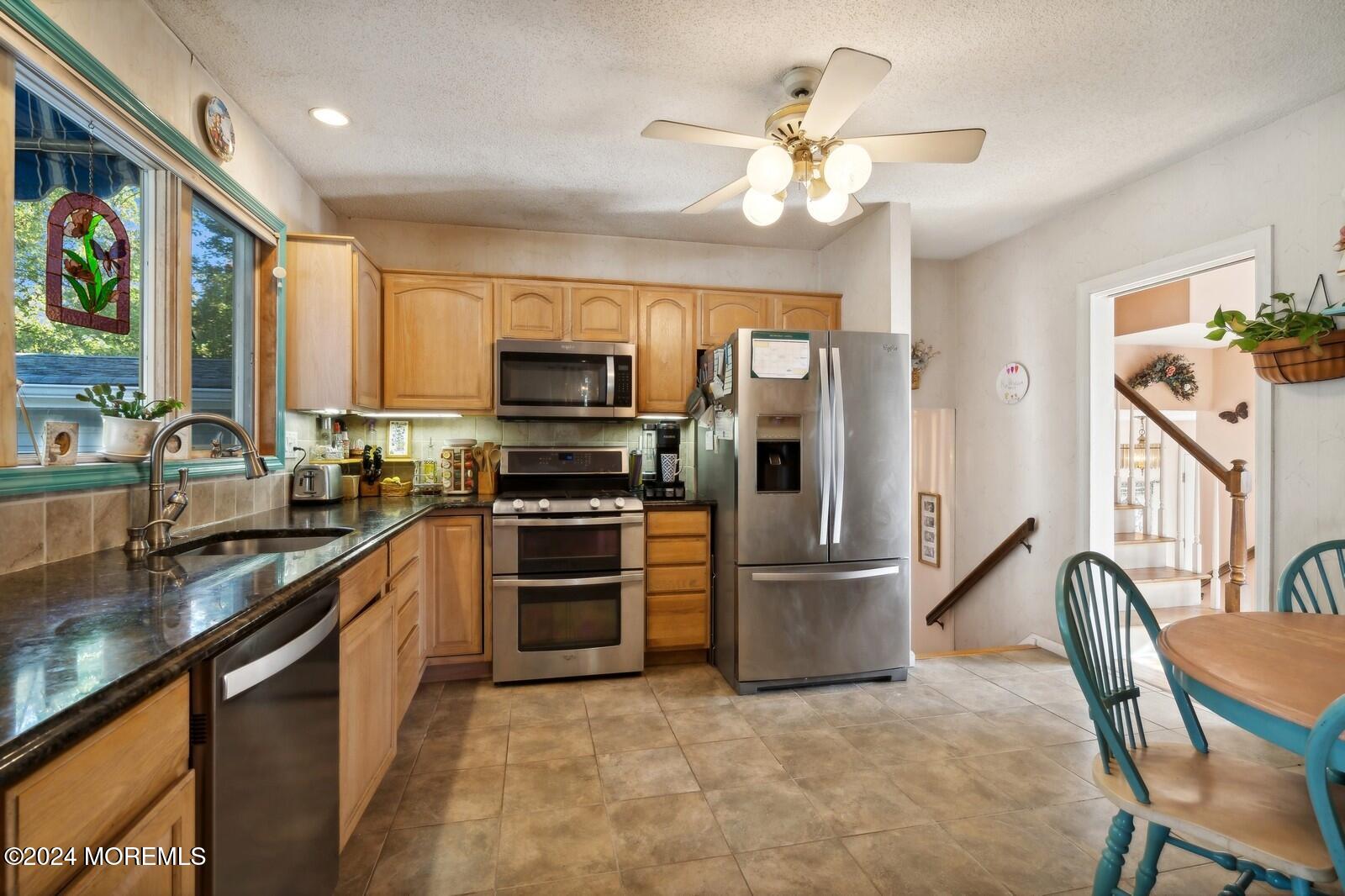 57 Pelican Road Middletown, NJ 07748 - Photo 3 of 49 a kitchen with stainless steel appliances granite countertop a refrigerator a stove a sink a dining table and chairs with wooden floor