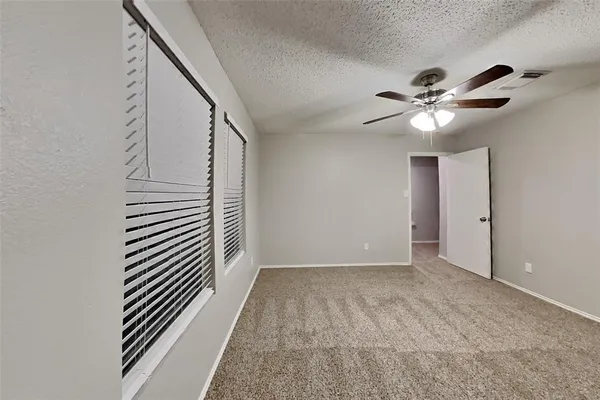 a view of an empty room with chandelier fan