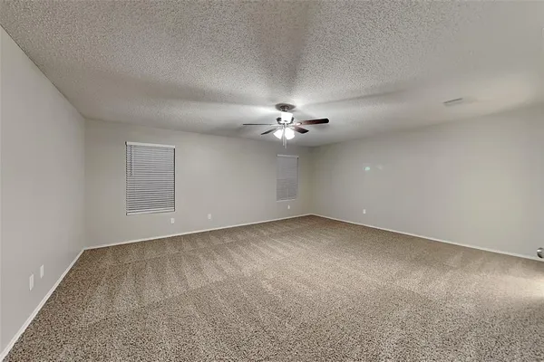 an empty room with a chandelier fan and windows
