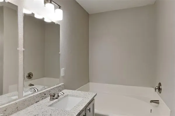 a bathroom with a granite countertop tub sink and mirror
