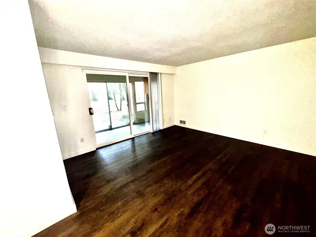 a view of an empty room with wooden floor and a window