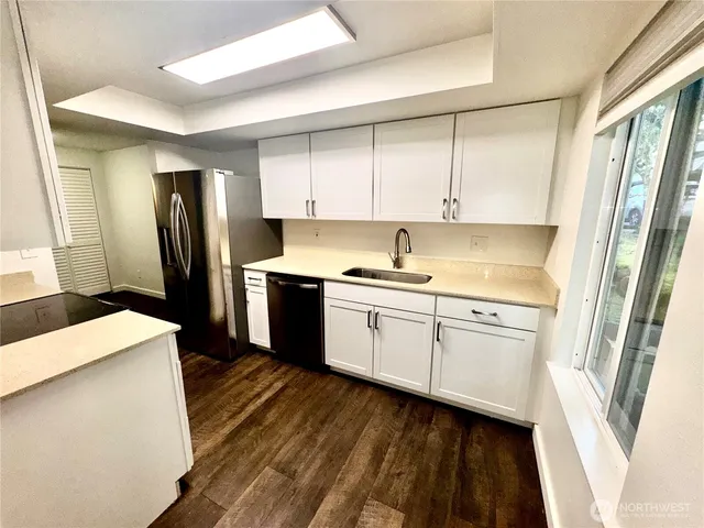 a kitchen with a sink a refrigerator a stove and white cabinets