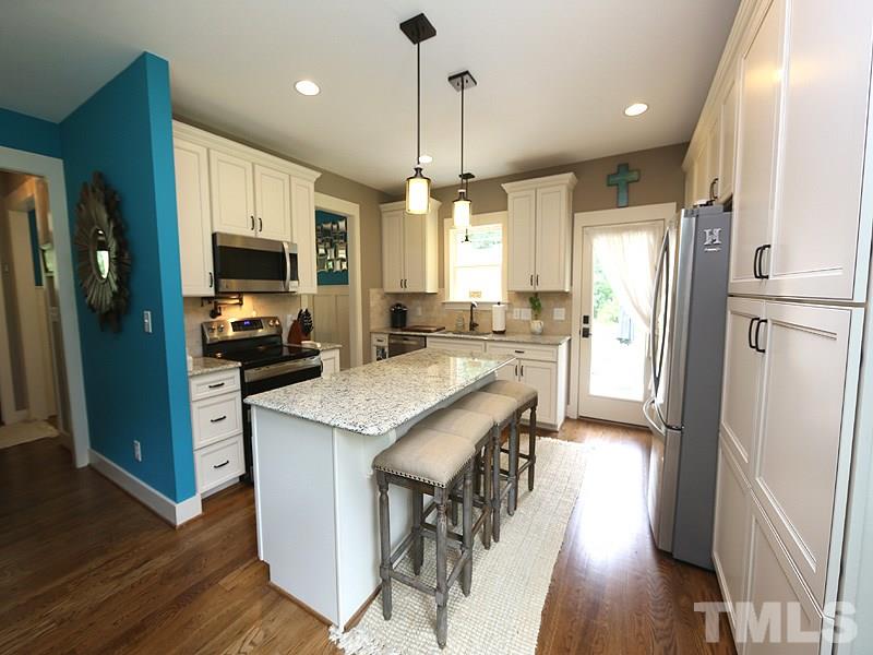 7401 Denlee Road Raleigh, NC 27603 - Photo 4 of 25 a kitchen with stainless steel appliances granite countertop a refrigerator a sink dishwasher a stove and a dining table with wooden floor