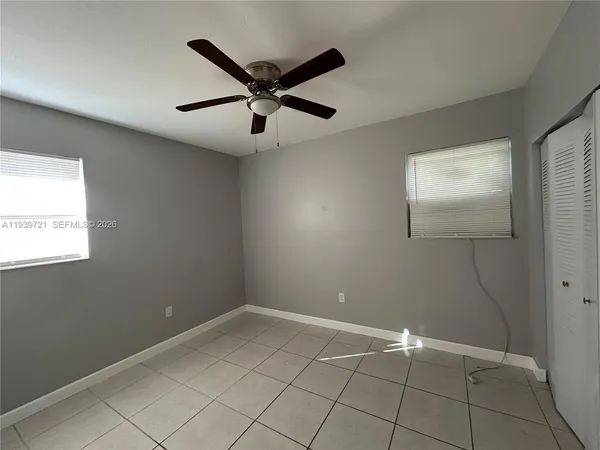 an empty room with windows and fan
