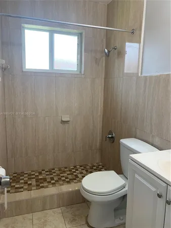 a bathroom with a sink a toilet a window and shower