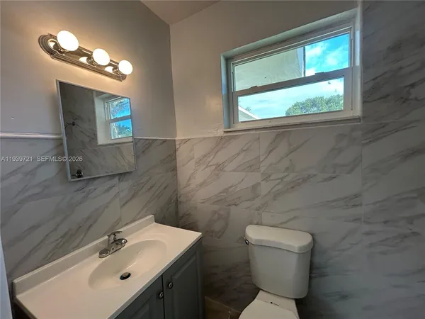 a bathroom with a toilet a sink a mirror and a window