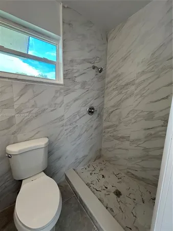a white toilet sitting next to a shower