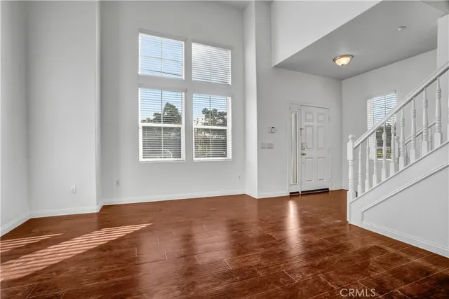 a view of an empty room with wooden floor fireplace and a window