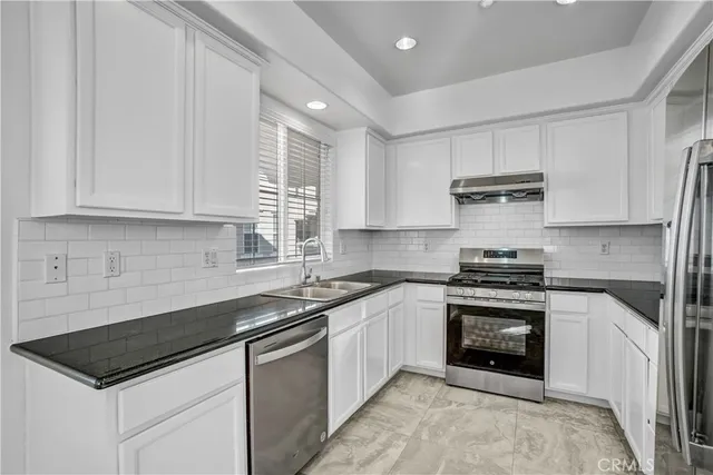 a kitchen with stainless steel appliances granite countertop a stove a refrigerator and a sink