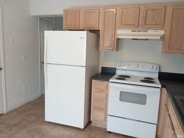 a white refrigerator freezer and a stove sitting inside of a kitchen