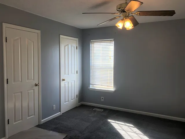 an empty room with windows and fan