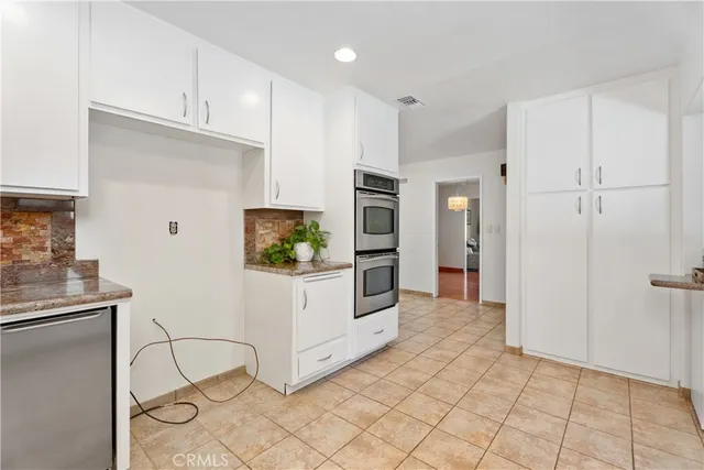a kitchen with white cabinets and refrigerator