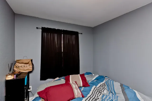 a bedroom with a bed and a lamp on the dresser
