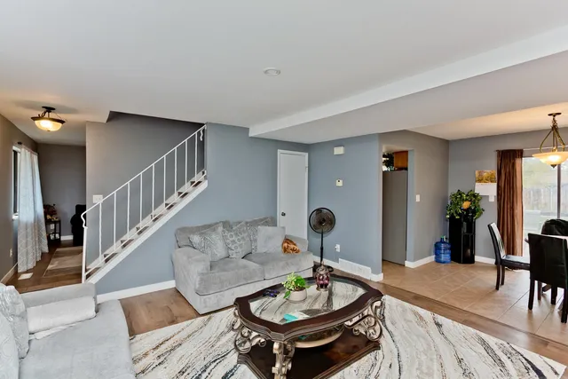 a living room with furniture and a dining table with wooden floor