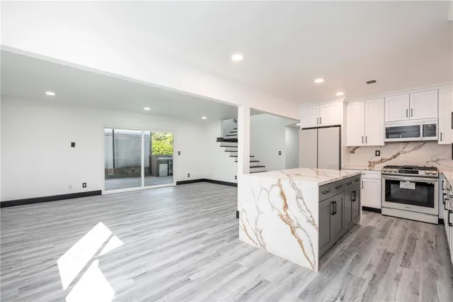 a large kitchen with stainless steel appliances granite countertop a large center island and a stove top oven