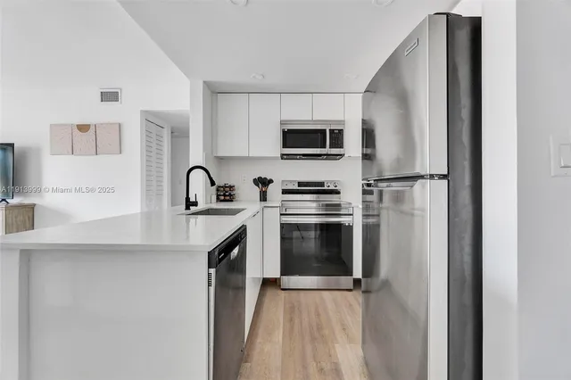 a kitchen with stainless steel appliances a refrigerator sink and microwave