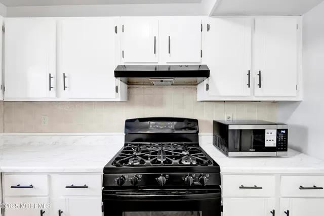 a kitchen with granite countertop white cabinets and stainless steel appliances