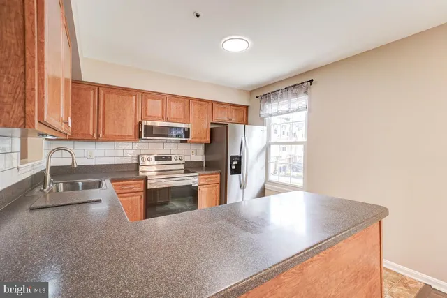a kitchen with stainless steel appliances granite countertop a refrigerator a stove top oven a sink and dishwasher