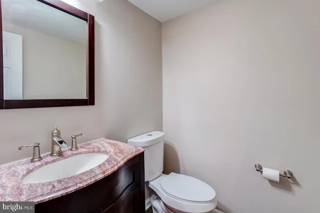 a bathroom with a granite countertop toilet sink and mirror