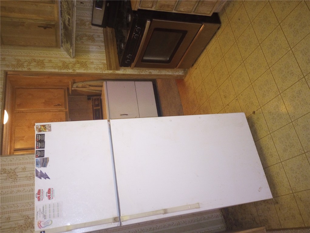 1682 Toro Road Bullhead City, AZ 86442 - Photo 5 of 30 Kitchen with freestanding refrigerator, range, wallpapered walls, washer / clothes dryer, and exhaust hood