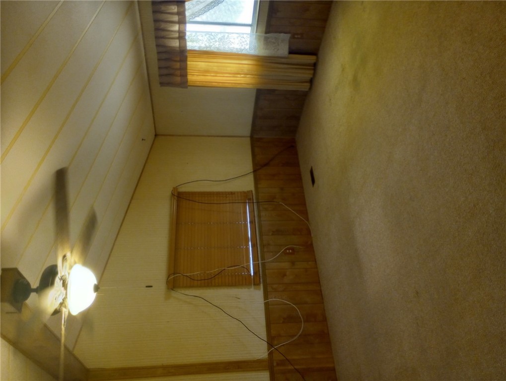 1682 Toro Road Bullhead City, AZ 86442 - Photo 7 of 30 Spare room with lofted ceiling, a ceiling fan, wood walls, and carpet