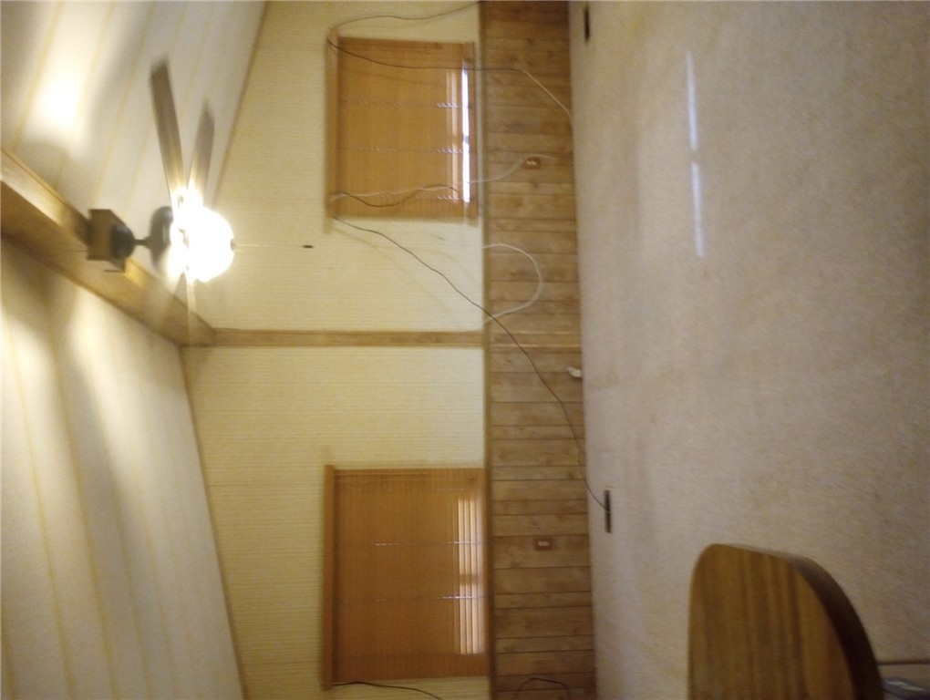 1682 Toro Road Bullhead City, AZ 86442 - Photo 9 of 30 Unfurnished room featuring carpet flooring, lofted ceiling, ceiling fan, wallpapered walls, and wood walls
