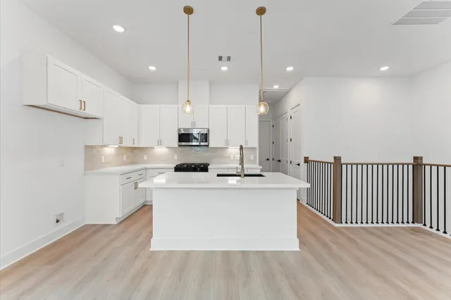 a kitchen with kitchen island granite countertop a sink a stove and cabinets