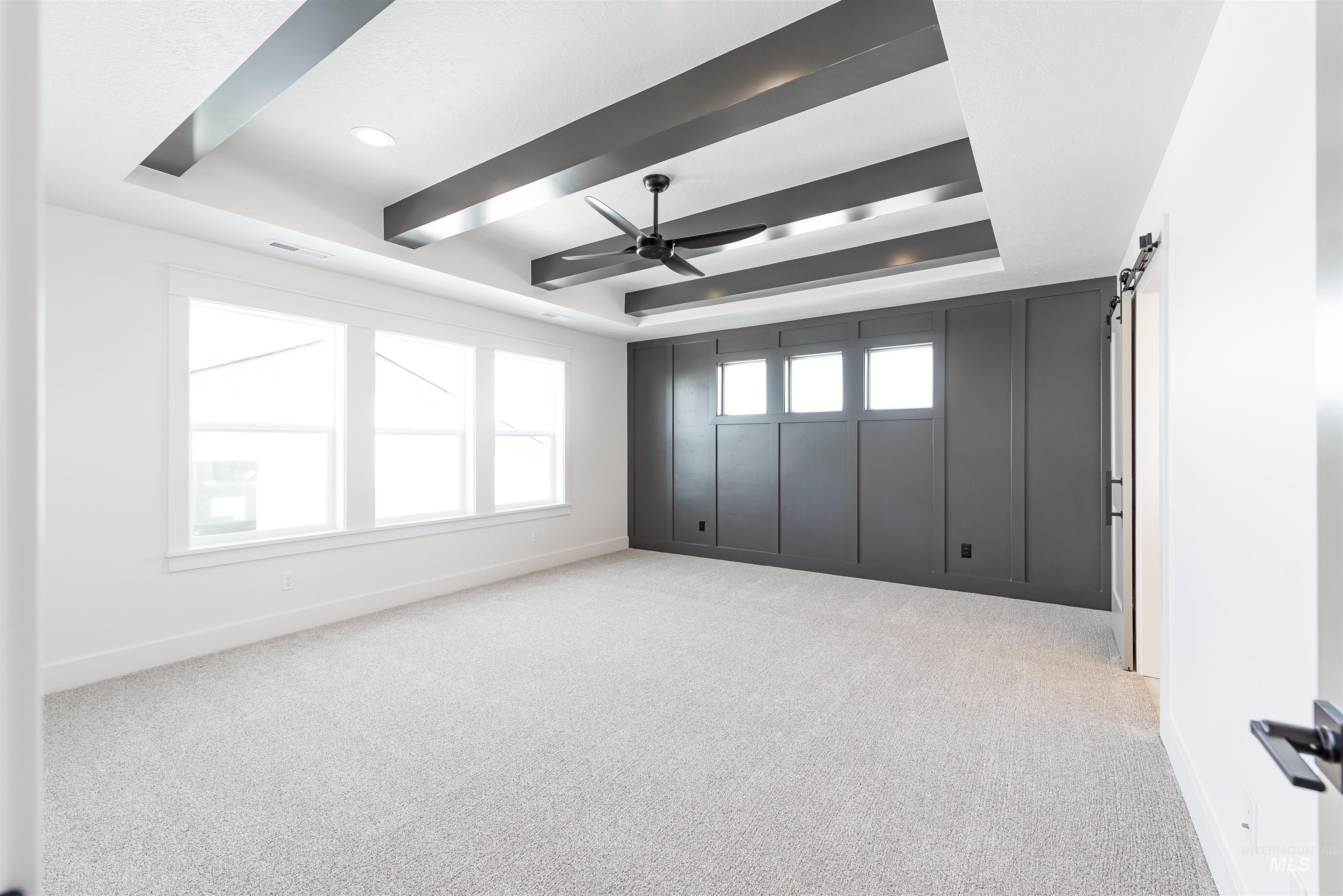 410 South Diesel Way Boise, ID 83716 - Photo 25 of 49 Spare room featuring a barn door, a tray ceiling, light carpet, and a ceiling fan