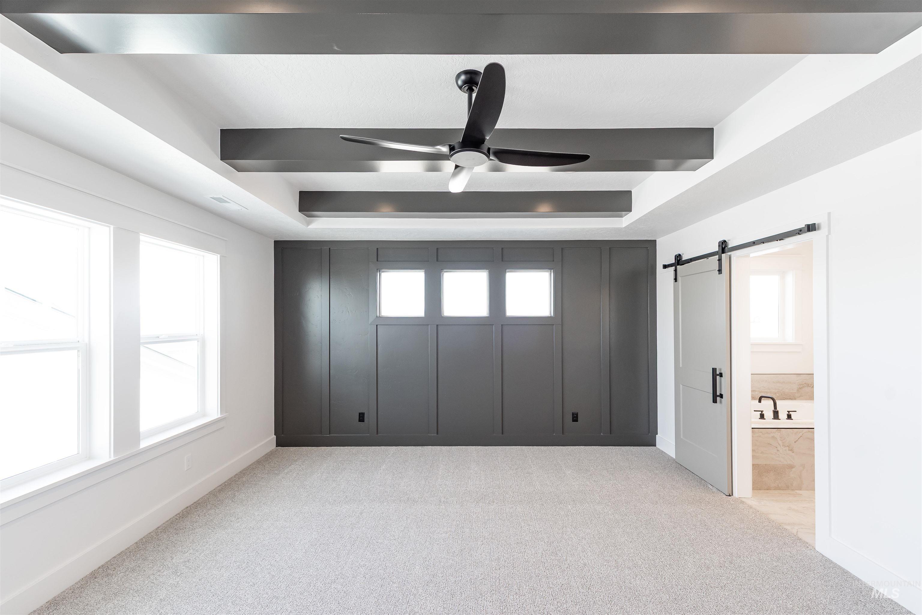 410 South Diesel Way Boise, ID 83716 - Photo 26 of 49 Unfurnished bedroom featuring a barn door, light colored carpet, a tray ceiling, ensuite bathroom, and ceiling fan