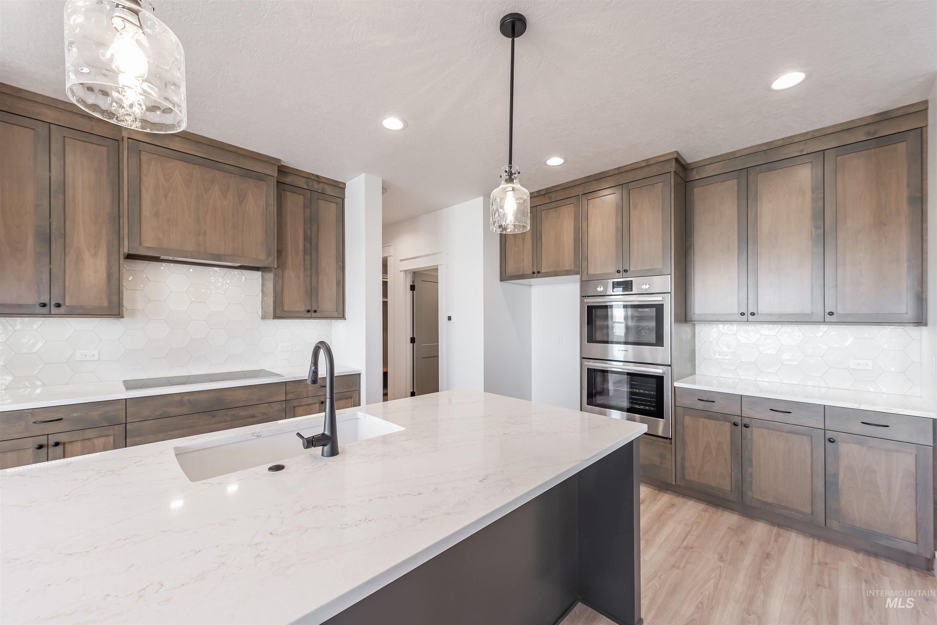 410 South Diesel Way Boise, ID 83716 - Photo 9 of 49 Kitchen featuring backsplash, light stone counters, stainless steel double oven, and light wood-style floors