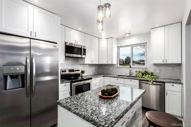 a kitchen with a stainless steel appliances granite countertop a sink stove and refrigerator