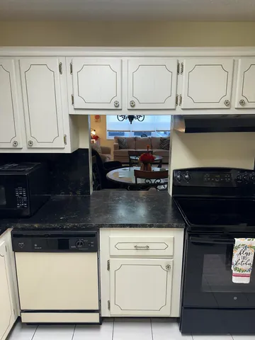 a kitchen with granite countertop white cabinets and black appliances