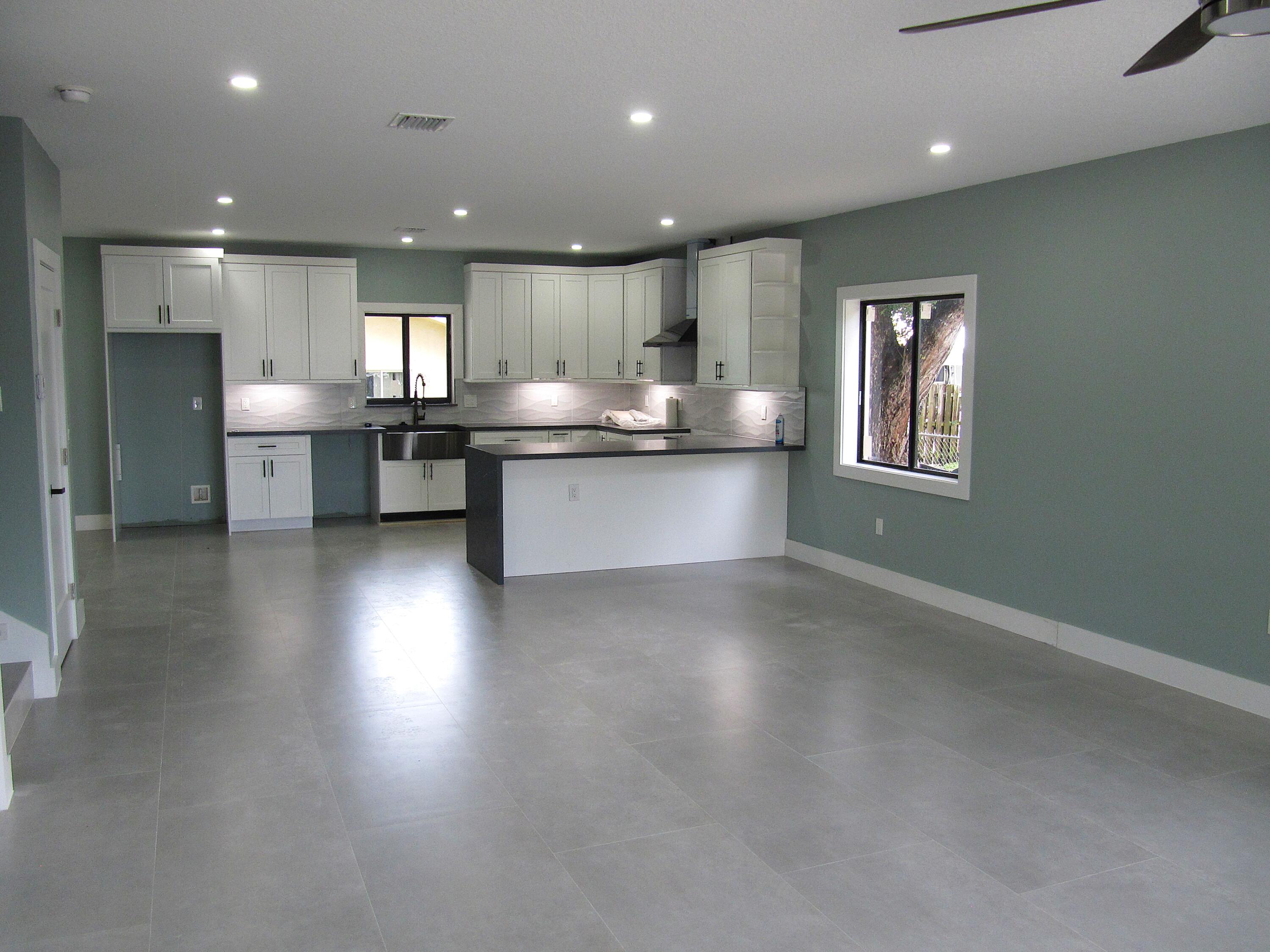 25 Abaco Road Key Largo, FL 33037 - Photo 14 of 17 a open kitchen with stainless steel appliances granite countertop a refrigerator a sink dishwasher a stove and a dining table with wooden floor