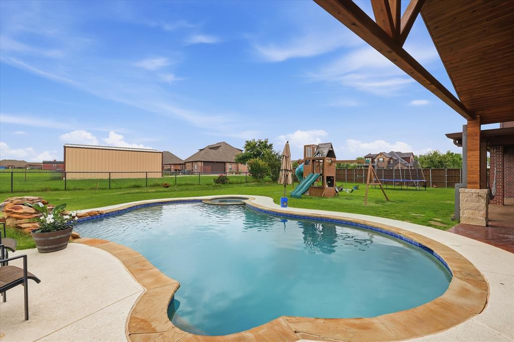 430 Ridgecrest Place Sanger, TX 76266 - Photo 31 of 40 Backyard oasis featuring a curvilinear swimming pool with integrated spa, concrete decking, and stone coping