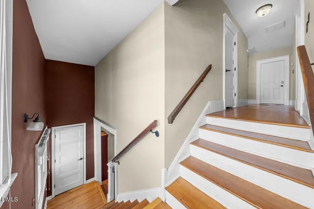 a view of staircase with lots of frames on wall and wooden floor