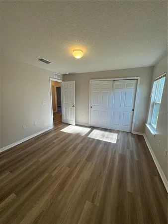 a view of empty room with wooden floor and fan